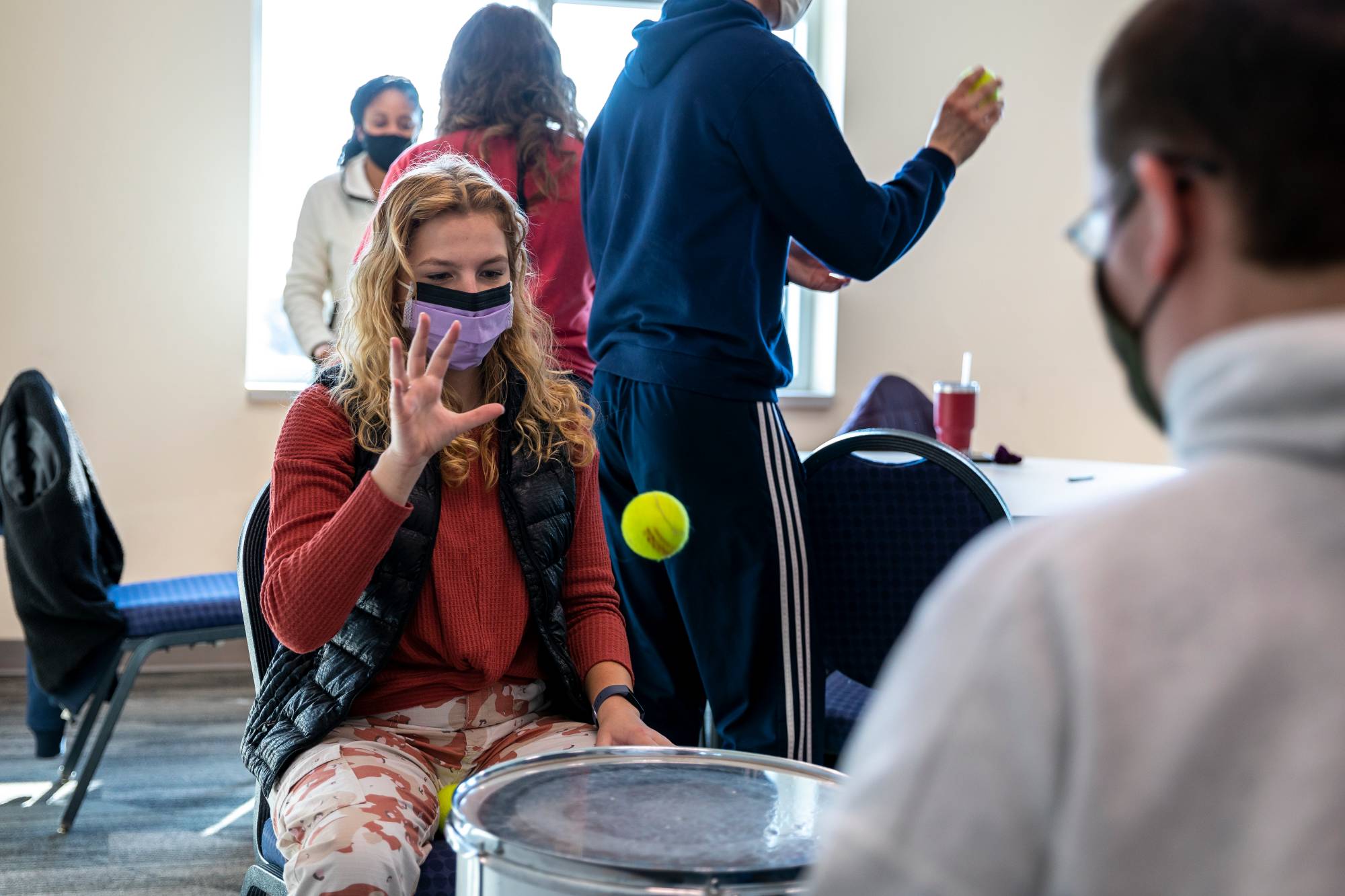 Students throwing a tennis ball on a drum